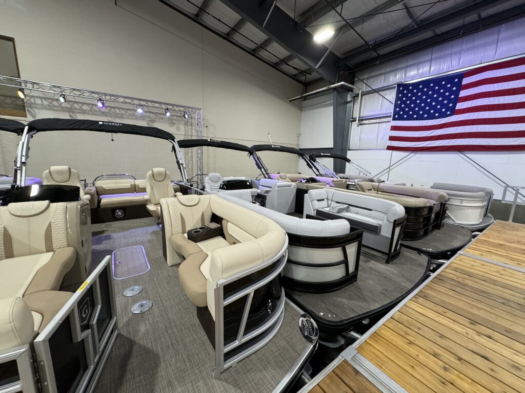 Lineup of Godfrey pontoons displayed indoors at The Boat House booth during the 2025 Northern Illinois Boat Show. 